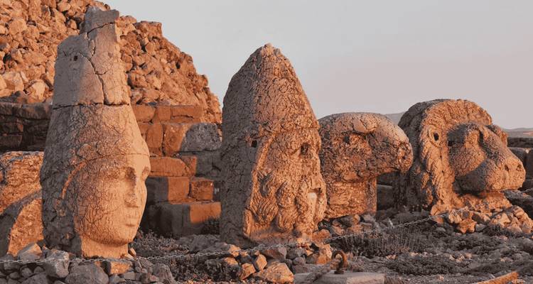 Ancient stone statues under sunset lighting.