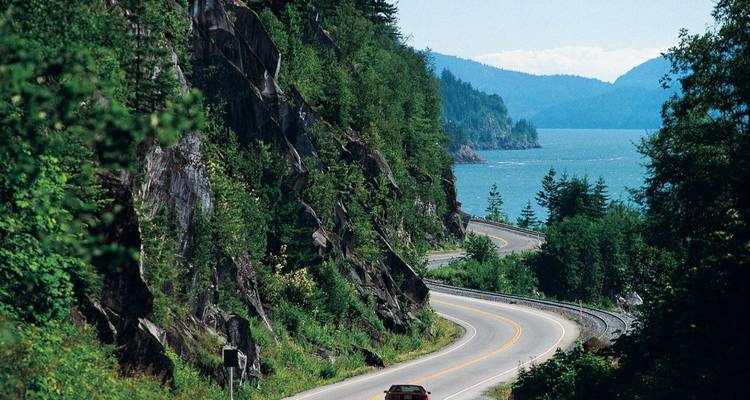 Kurvenreiche Straße entlang eines Berghangs mit Blick auf den See.