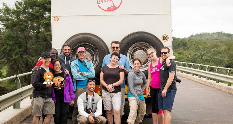 Groupe de touristes debout devant un autocar de tourisme.