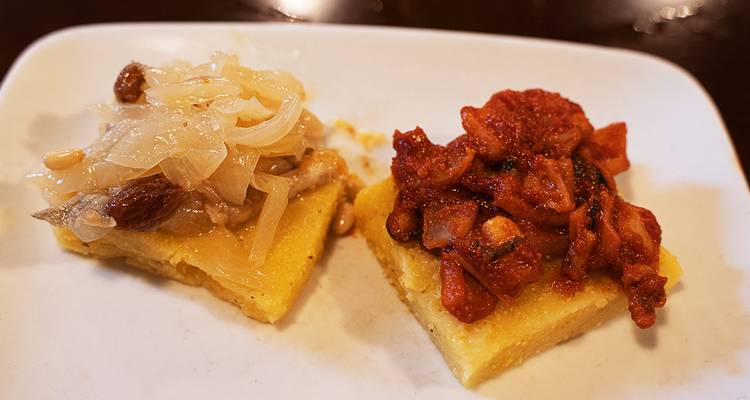 Plate with Italian appetizers, onions and tomatoes on bread.