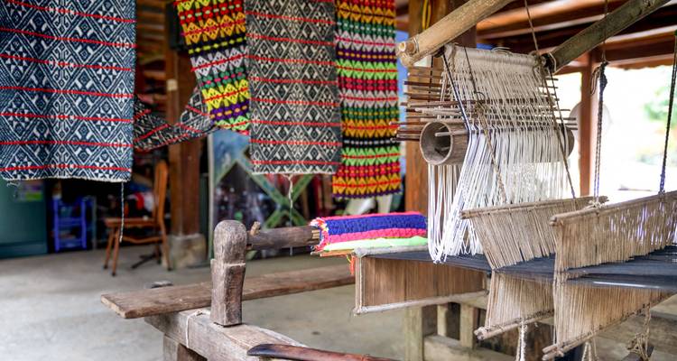 Textiles tissés traditionnels suspendus dans un atelier.