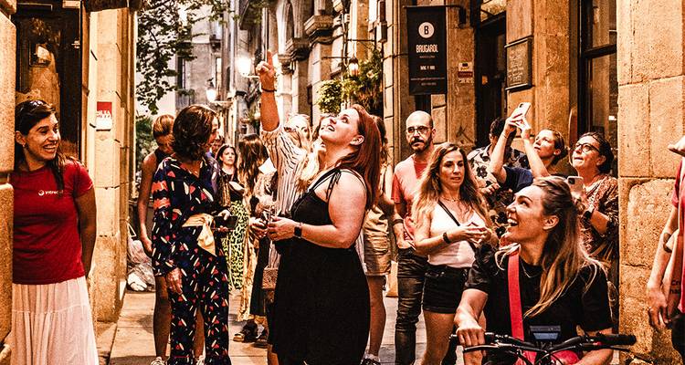A group of people walking and taking photos in a lively street.