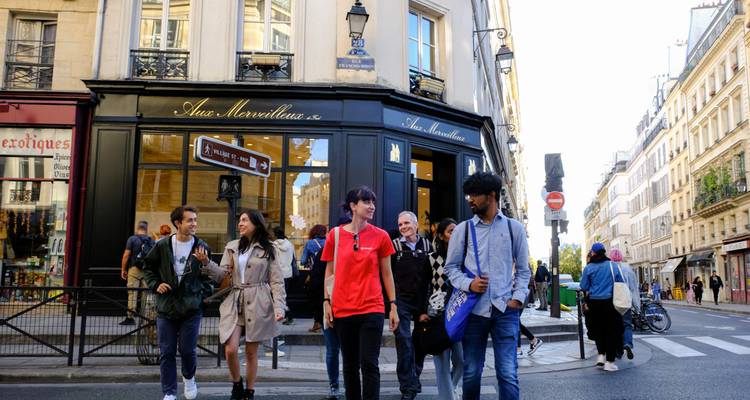 Groupe de personnes passant devant des magasins dans une rue de Paris.