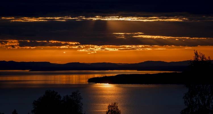 Coucher de soleil doré spectaculaire sur un lac avec des nuages.