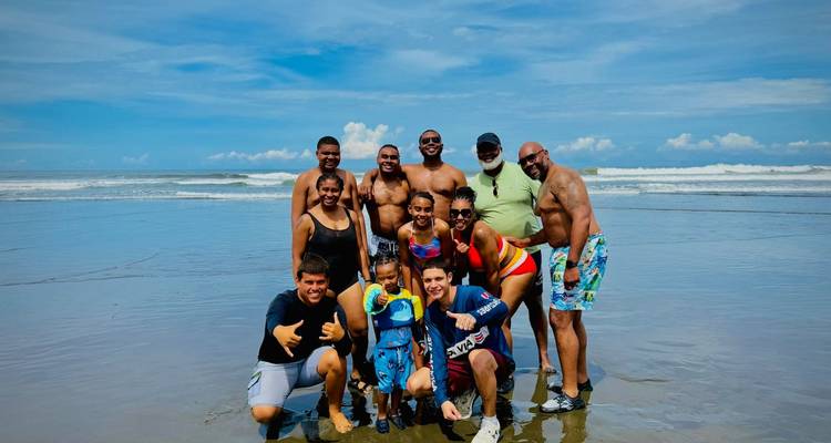 Un groupe de personnes posant sur une plage avec l'océan en arrière-plan.