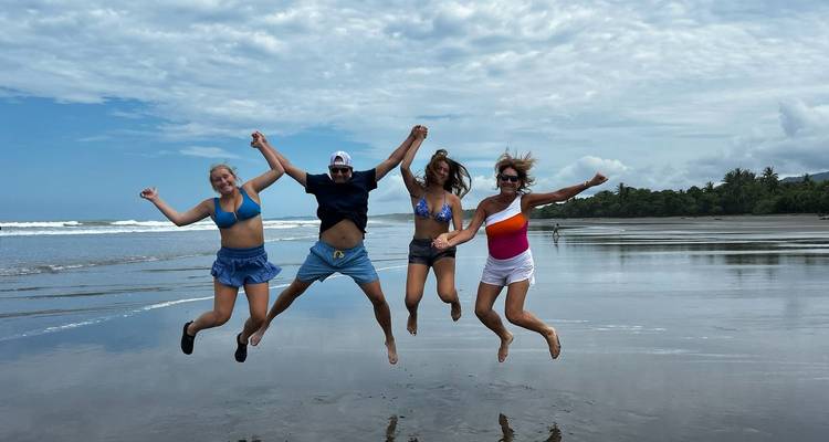 Quatre personnes sautant sur une plage avec l'océan en arrière-plan.