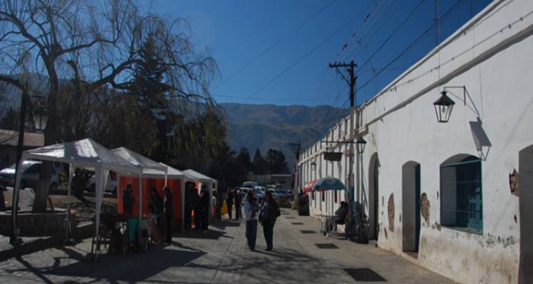 Een straatmarktscène met mensen en tenten op een zonnige dag.