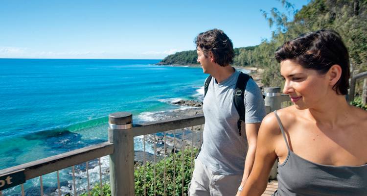 Couple se promenant le long d'une promenade côtière avec vue sur l'océan.