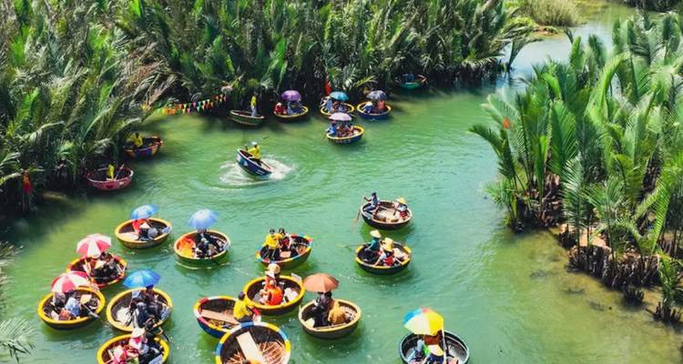 Tourists riding circular boats in a green river surrounded by palm trees.