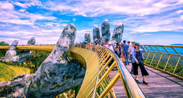 Tourists walking on the Golden Bridge held by stone hands.