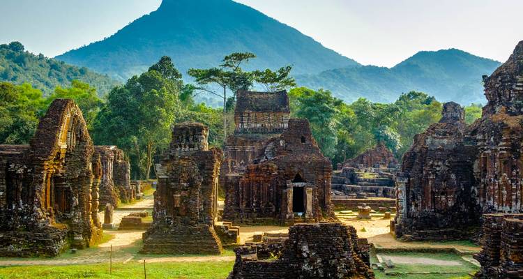 Ancient ruins with mountainous backdrop at sunrise.