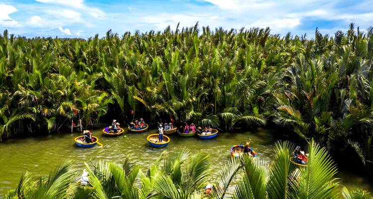 Tourists in colorful circular boats on a river surrounded by palms.