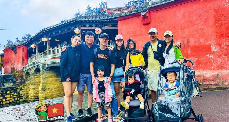 Gran familia con cochecitos frente al Puente Cubierto Japonés de paredes rojas.