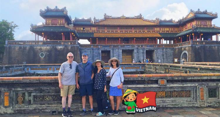 Cuatro viajeros de pie ante la ornamentada puerta principal de la Ciudadela Imperial de Hue.