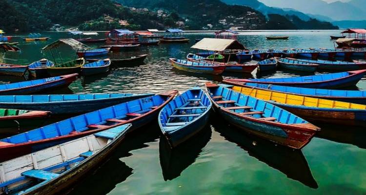 Barcos coloridos flotando en un lago tranquilo con montañas de fondo.