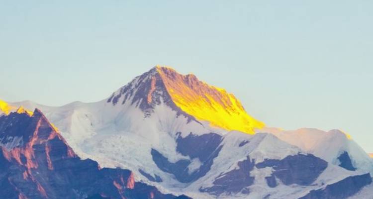 Pico de montaña resplandeciendo en la luz de la madrugada.