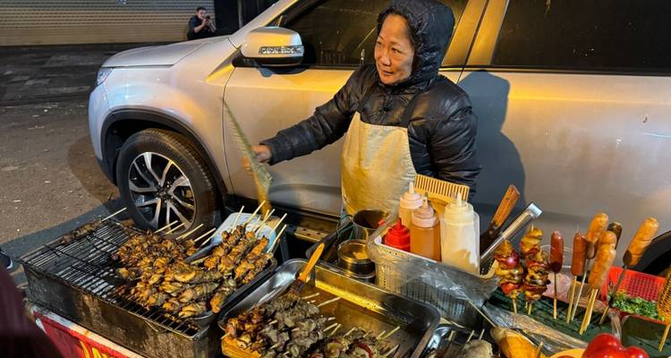 Vendor selling grilled skewers at a street stall.