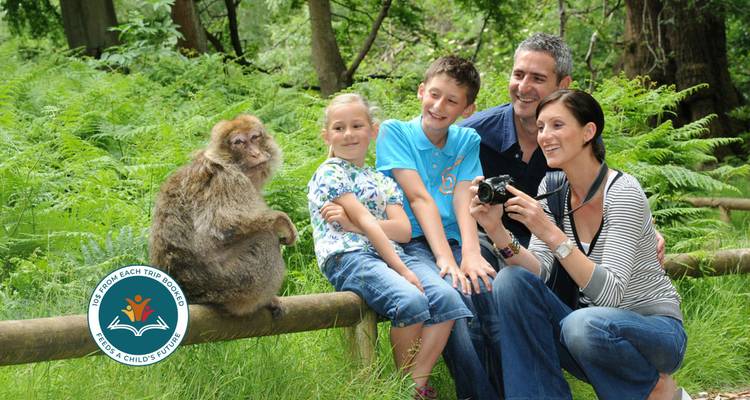 Family taking a photo with a monkey in a wooded area.