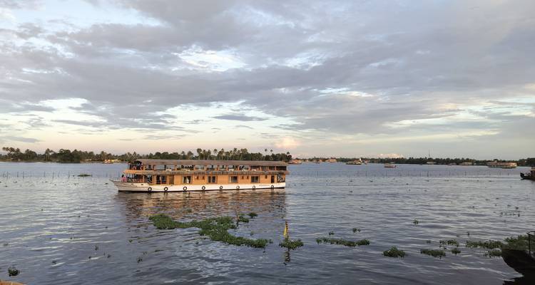 Houseboat on a river with a cloudy sky.