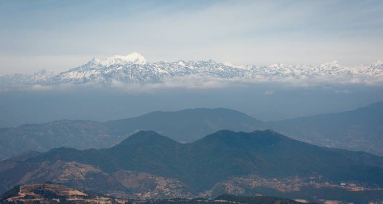 Vue panoramique de l'Himalaya avec des couches de collines and des sommets enneigés.