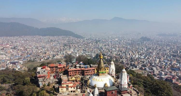 Vue aérienne du stupa de Swayambhunath entouré d'un paysage urbain.