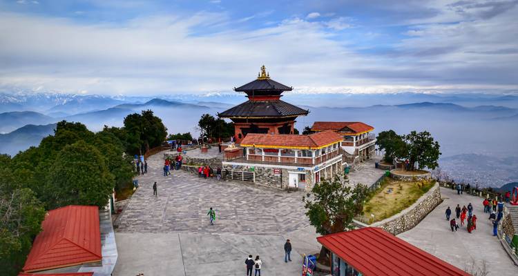 Touristes visitant une zone pittoresque au sommet d'une colline avec vue sur les montagnes.