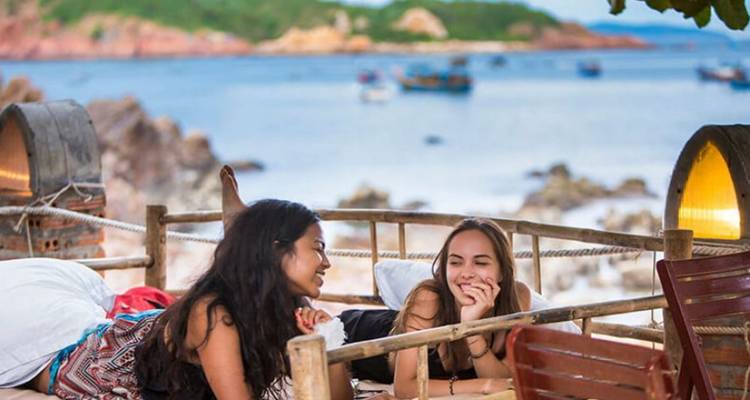 Two women relaxing in a wooden boat by the sea.