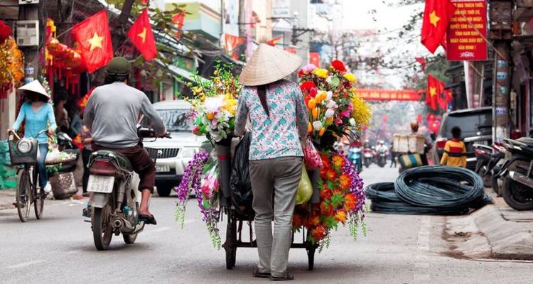 Street scene in Vietnam with a flower vendor and colorful flags.