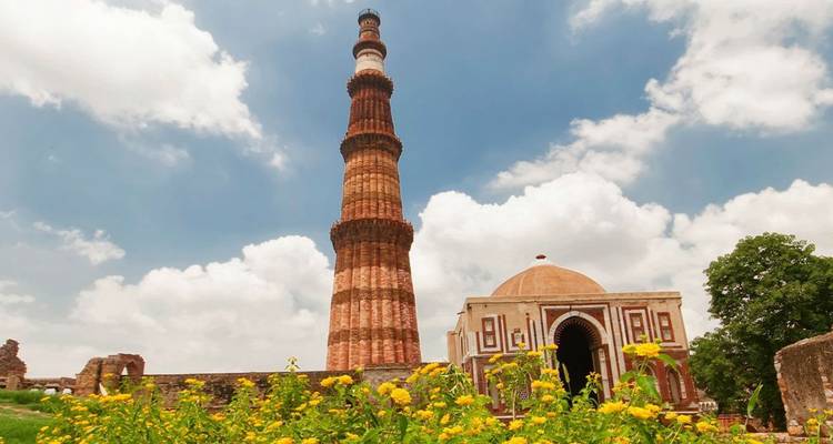 Qutub Minar mit umliegenden Gebäuden und Gärten.