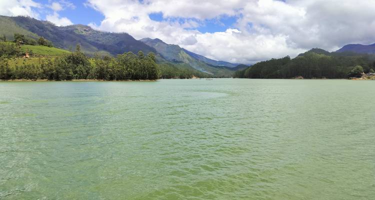 Vue pittoresque d'un lac entouré de forêts et de collines.