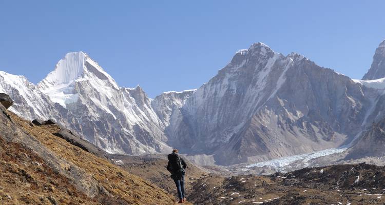 Person hiking in front of snow-capped mountains.