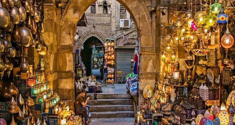 Scène de marché colorée avec diverses lampes et une personne assise.