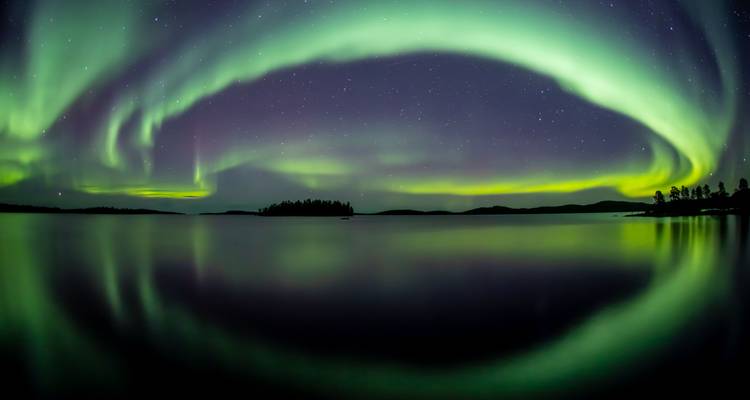 Aurore boréale reflétée sur un lac la nuit.