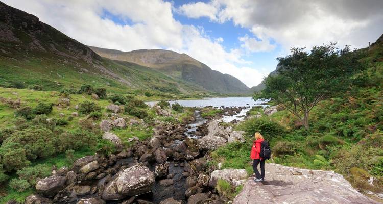 A person in a red coat walking through a picturesque landscape in Ring of Kerry, Ireland.