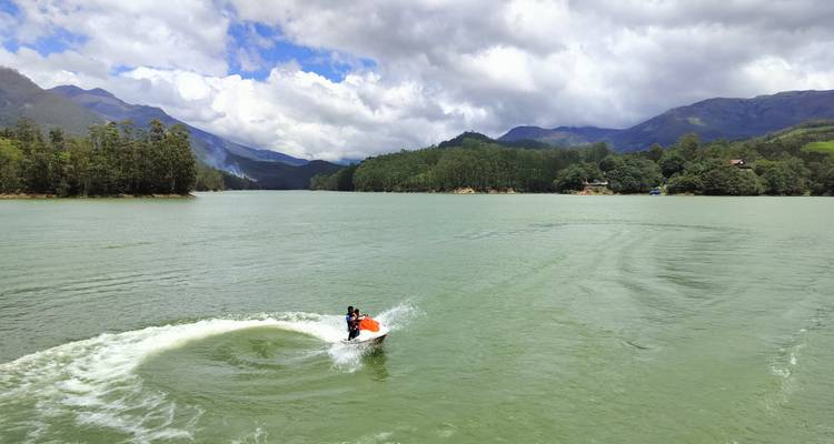 Jet ski sur un lac entouré de collines boisées.