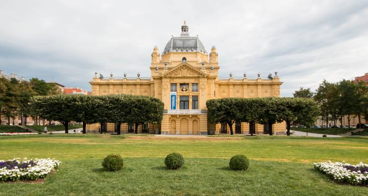 Architectural building with manicured gardens in front.