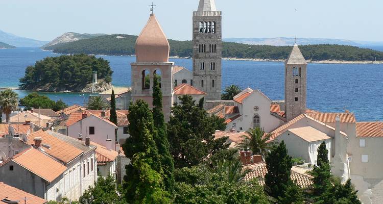 Scenic view of historical clock towers amidst lush vegetation by the sea.