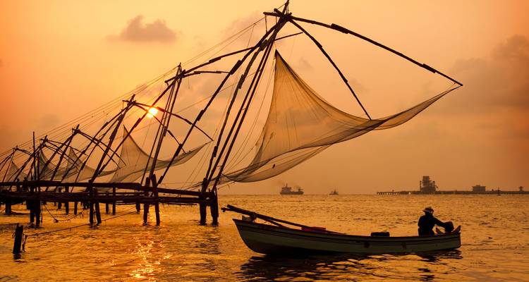 Silhouette d'un pêcheur avec des filets de pêche chinois au coucher du soleil.