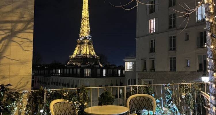 Vue nocturne de la tour Eiffel depuis un balcon avec des sièges.