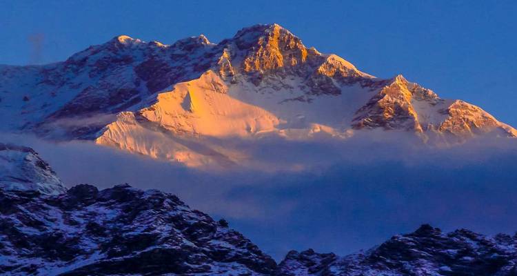 La lumière du soleil frappant un pic de montagne enneigé au lever du soleil.