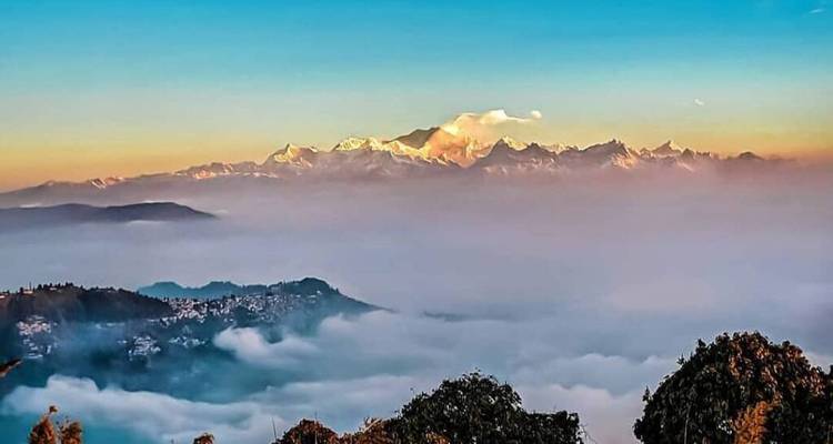 Une vue lointaine de montagnes couvertes de brume sous un ciel doré.