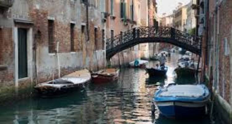 Petit canal avec des bateaux et un pont voûté.