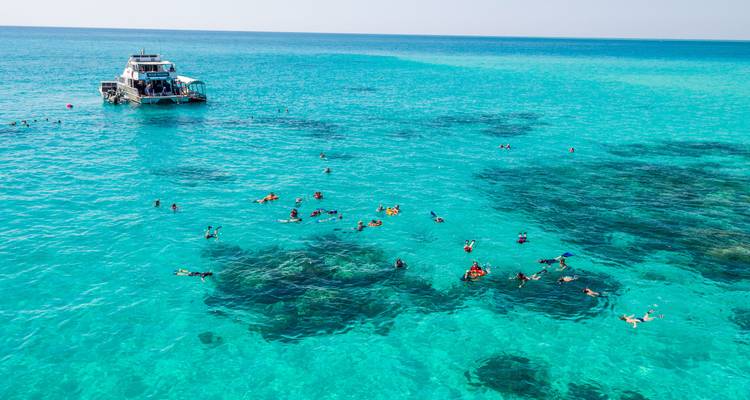 Plongée avec tuba près d'un bateau dans un océan turquoise.