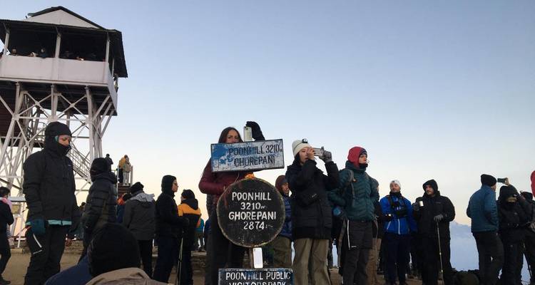 Des gens se sont rassemblés près d'un point de vue avec un panneau indiquant Poon Hill.