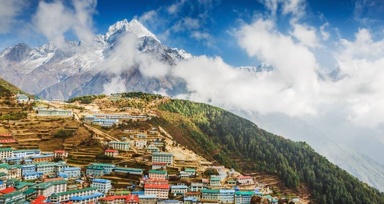 Pueblo enclavado en los Himalayas bajo un cielo azul con nubes.