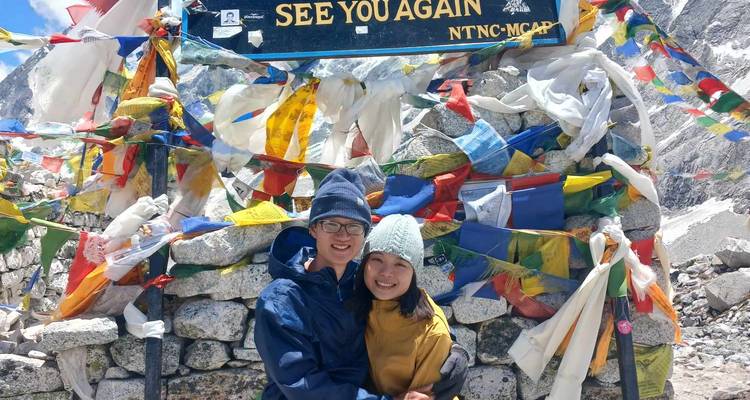 Couple posing with the Larke Pass sign and prayer flags.