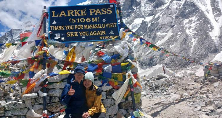 People posing at Larke Pass with flags and a sign.