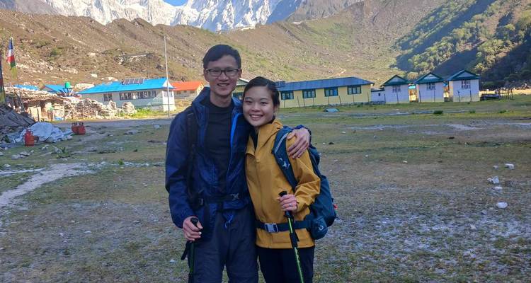 A couple in hiking gear at a base camp with buildings.