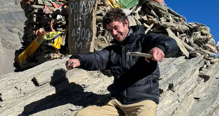 Man sitting on rocks at a high altitude point.