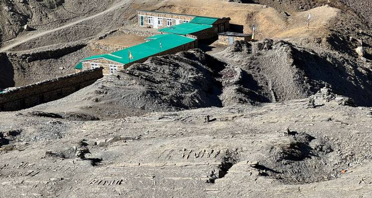 Mountain lodge with turquoise roofs situated among rocky terrain.